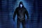 Hacker person in black hood on binary code backdrop