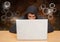 Hacker using a laptop in front of digital orange background