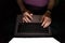 Hacker using laptop. hands typing on PC late at night, view from above. Unrecognizable girl, sitting in a dark room. Bright from