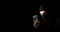 Hacker Using Smart Phone. Young adult girl in black clothes with hidden face looks at smartphone screen on black background with c