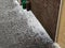 Hail lies on pavement near a house