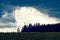 Hailstorm brewing over spring meadow and forest in German countryside