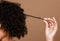 Hair care, beauty and black woman hand with curly hair on brown background in studio. Hair salon, wellness and girl