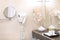 A hair dryer and a shelf for personal hygiene items in the bathroom. Flowers and a mirror are out of focus. The concept of the