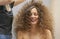 The hair master makes a hairstyle for a woman. Portrait of a beautiful Caucasian girl with flowing curly hair. The