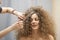 The hair master makes a hairstyle for a woman. Portrait of a beautiful Caucasian girl with flowing curly hair. The