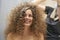 The hair master makes a hairstyle for a woman. Portrait of a beautiful Caucasian girl with flowing curly hair. The