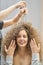 The hair master makes a hairstyle for a woman. Portrait of a beautiful Caucasian girl with flowing curly hair. The
