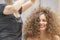 The hair master makes a hairstyle for a woman. Portrait of a beautiful Caucasian girl with flowing curly hair. The