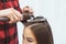 Hair stylist barber styling long hair with hair iron for beautiful young asian woman with cup of tea in beauty salon, working