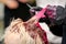 Hair stylist dying hair of woman with pink dye