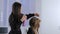 Hair stylist, hairdresser finishing hairstyle for young pretty woman