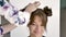 Hair stylist makes a young beautiful caucasian brunette`s hairstyle