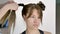 Hair stylist makes a young beautiful caucasian brunette`s hairstyle