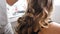 Hair stylist making curls on customer hair using electric curler