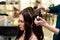 Hair stylist making ringlets to brunette woman. Hairdresser work