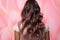 Hair transformation Model\\\'s back view ƒ?? repair, shine, volume emphasized on pink backdrop.