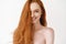 Haircare. Beautiful young woman with long healthy red hair smiling at camera. Pale female model looking happy, posing