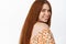 Haircare and women beauty. Natural young redhead girl smiling happy, turn head at camera with gentle gaze, white