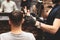 Haircut head in barbershop. Barber cuts the hair on head of client. The process of creating hairstyles for men. Selective focus.