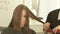 Haircutter combing and cutting woman hair with hairdressing scissors in beauty studio. Close up hairstylist making