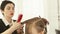 Haircutter combing long hair during female haircut in hairdressing salon. Close up woman hairstyle in beauty salon