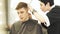 Haircutter shaving hair during male hairdressing in barber shop. Hairdresser doing professional hairstyle with shaver in