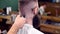 Haircutting with clipper, shaking off hair with brush from back of head. Cropped close up of haircutting in barbershop