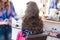 Hairdresser applying hairspray for long curly hair of woman