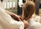 Hairdresser Braiding Young Woman`s Hair In Beauty Salon, Closeup