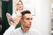 Hairdresser and client evaluate result after haircut. Stylist doing hair styling for guy