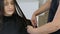 Hairdresser combing and cuting hair of teen girl client in hair salon
