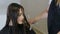 Hairdresser combing and cutting hair of teen girl client in hair salon