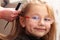 Hairdresser combing hair little girl child in hairdressing beauty salon