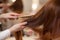 Hairdresser combing her long, red hair of his client in the beauty salon.