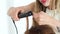 Hairdresser curling using hair tongs close up. Process curling with hair iron in beauty studio. Hairstylist doing