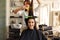 Hairdresser curls and combs woman`s hair