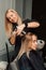 A hairdresser cuts a blonde& x27;s hair in a beauty salon. Women& x27;s haircut
