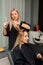 A hairdresser cuts a blonde& x27;s hair in a beauty salon. Women& x27;s haircut