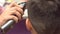 Hairdresser cuts hairs with clipper on man`s head. Back view, stylist`s hands close-up.