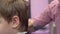 Hairdresser cuts hairs with scissors on boy`s head. Side view, stylist`s hands close-up.