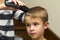 Hairdresser is cutting hair of a child boy in barber shop