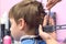 Hairdresser cutting hairs with scissors on boy`s head. Back view, stylist`s hands close-up.