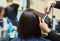 The hairdresser does aligns the hair with hair iron to a young girl, brunette in a beauty salon