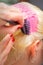 Hairdresser dyes hair of young woman in pink color