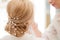 Hairdresser finishing bride`s hairstyle