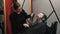 a hairdresser girl using a hair dryer to dry a man& x27;s long beard in a barbershop