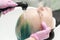 Hairdresser hands wash long hair of customer with green and discolored hair in sink with water from shower