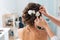 Hairdresser makes an elegant hairstyle styling bride with white flowers in her hair