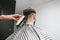 Hairdresser makes a haircut to man using a trimmer. Barber cuts the client. Hand with a clipper shaves hair from the back of the